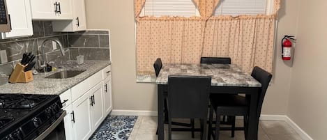A compact kitchen with a gas stove, sink, and white cabinets.