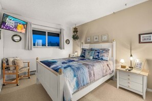 A bedroom with a bed, a TV, a bedside table, a chair, and a window. - Sunny Delighthouse – Ocean View & Beach Access (Lincoln City)