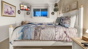A bedroom with a bed, a television, a window, and wall decorations. - Sunny Delighthouse – Ocean View & Beach Access (Lincoln City)