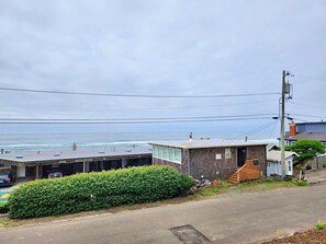 A coastal property with a small house, a covered parking area, and a view of the ocean.