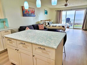 Une pièce comprenant un coin cuisine, une table à manger, un canapé et un balcon avec vue.