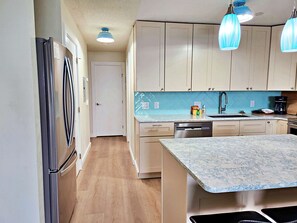 A kitchen with a refrigerator, cabinets, a dishwasher, and a countertop with a sink.