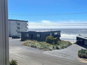 A coastal building with a parking area and a view of the ocean. - Studio w/ King Bed, Ocean Views, Pet Friendly! (Lincoln City)