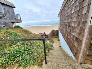 Eine Holztreppe führt zu einem Strand, mit Blick auf den Ozean.