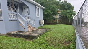 A house with a front porch, a staircase, and a fenced yard. - 2-bedroom house in delightful Lajas with AC (Lajas)