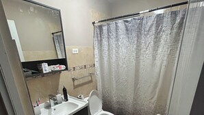 A bathroom with a sink, mirror, toilet, and shower curtain. - 2-bedroom house in delightful Lajas with AC (Lajas)
