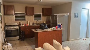 A kitchen with a stove, oven, refrigerator, and a small island with various items on it. - 2-bedroom house in delightful Lajas with AC (Lajas)