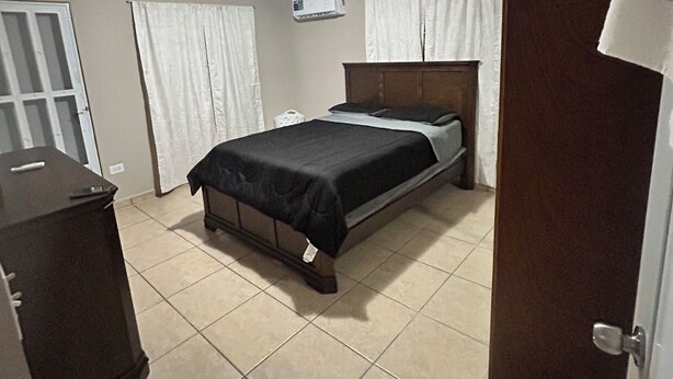 A bedroom with a bed, an air conditioner, a wardrobe, and a door. - 2-bedroom house in delightful Lajas with AC (Lajas)