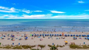 Uma praia com guarda-sóis e pessoas.