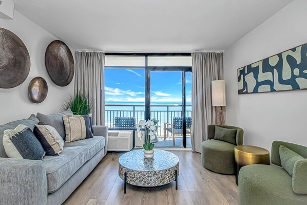 Un salón moderno con balcón, una mesa de centro redonda y vista al mar.