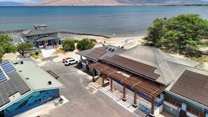 A coastal hotel with a view of the sea, a parking area, and a building with solar panels. - KBS A106 - Updated Studio next to Beach (Kihei)