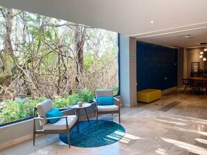 A modern hotel lobby with a large window, seating area, and a dining space. - Stunning Rooftop Views - Steps from the Sand (Playa del Carmen)