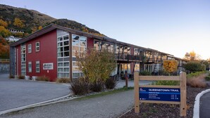 A red building with a sign for Marina Apartments. - 2BR Lakefront Apt in Queenstown | Wi-Fi & Parking (Queenstown)