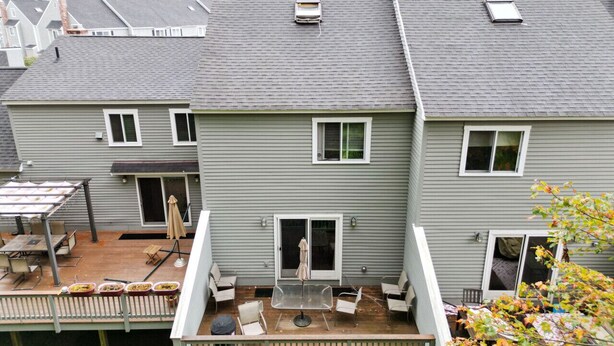 Een huis met twee verdiepingen, een patio en een overdekte zithoek, met een kleine tuin.