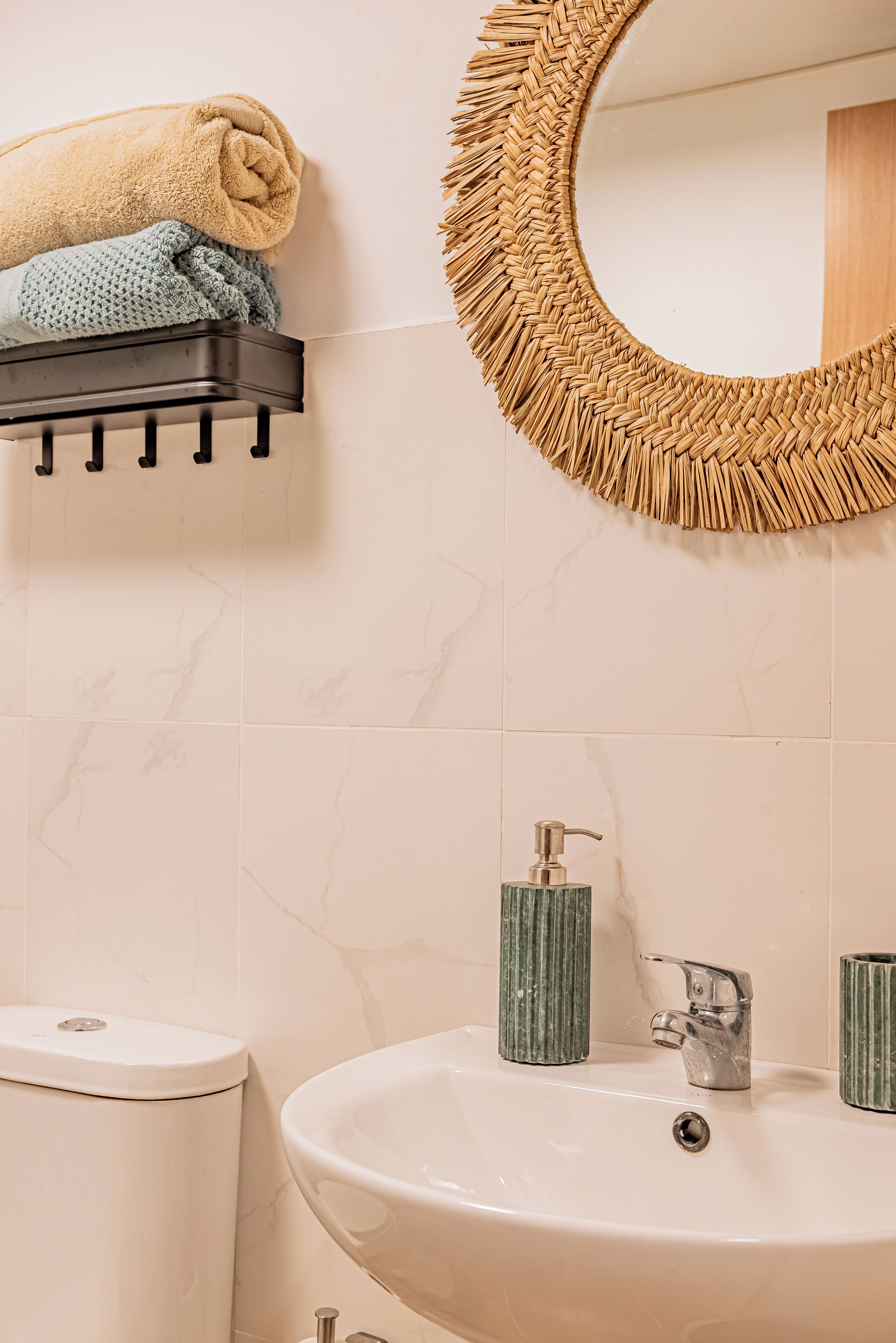 Ein Badezimmer mit Toilette, Waschbecken mit Spiegel und Handtuchhalter mit Handtüchern.