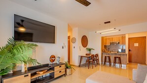 Una sala de estar moderna con televisor de pantalla plana, mueble de entretenimiento de madera y un sofá de color claro.