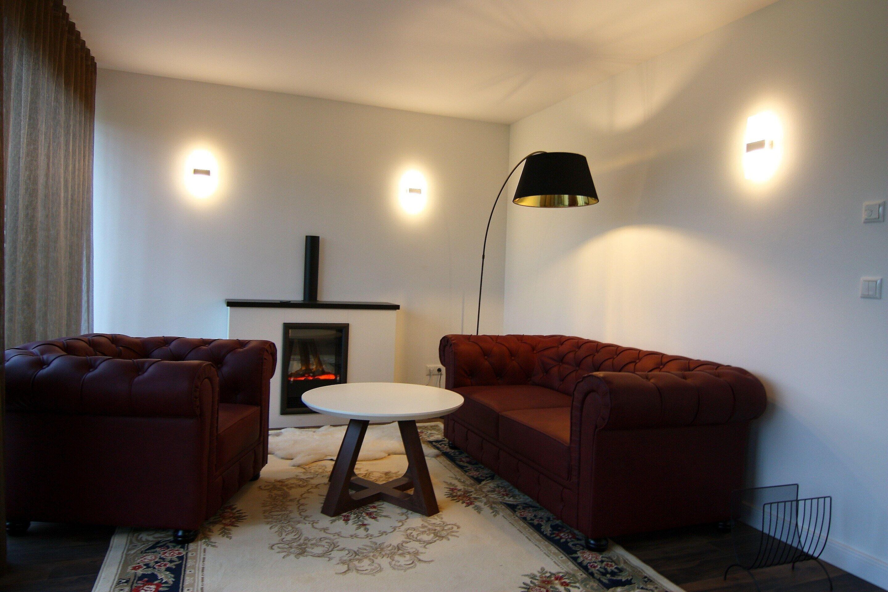 A living room with a fireplace, two sofas, a round table, and a floor lamp.