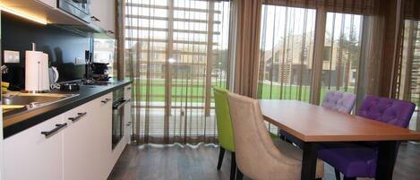 Cocina moderna con zona de comedor, que incluye una mesa y sillas, y ventanas grandes con cortinas.