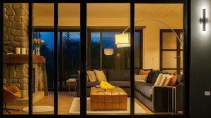 Una sala de estar moderna con chimenea de piedra, un conjunto de sofá, una mesa de centro y un ventanal con vistas al exterior.