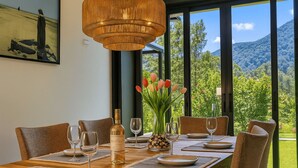 Mesa de comedor preparada para seis personas, con una botella de vino, tulipanes y un cuadro en la pared.