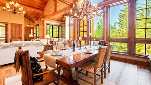 A wooden dining room with a large table set for six, surrounded by wicker chairs.