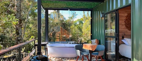 A modern outdoor deck with a hot tub, seating area, and a grill.