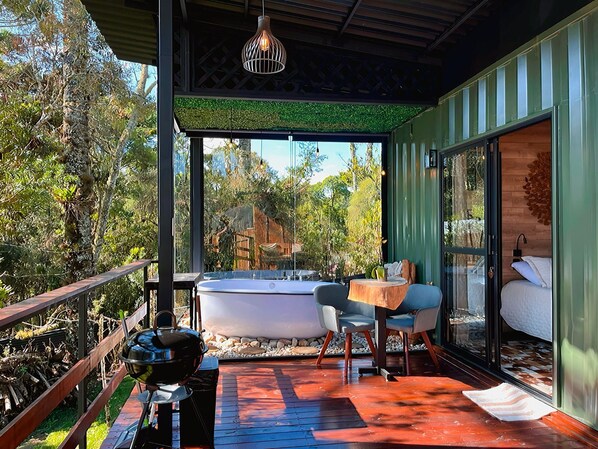 Una terraza moderna al aire libre con jacuzzi, zona de estar y una parrilla.