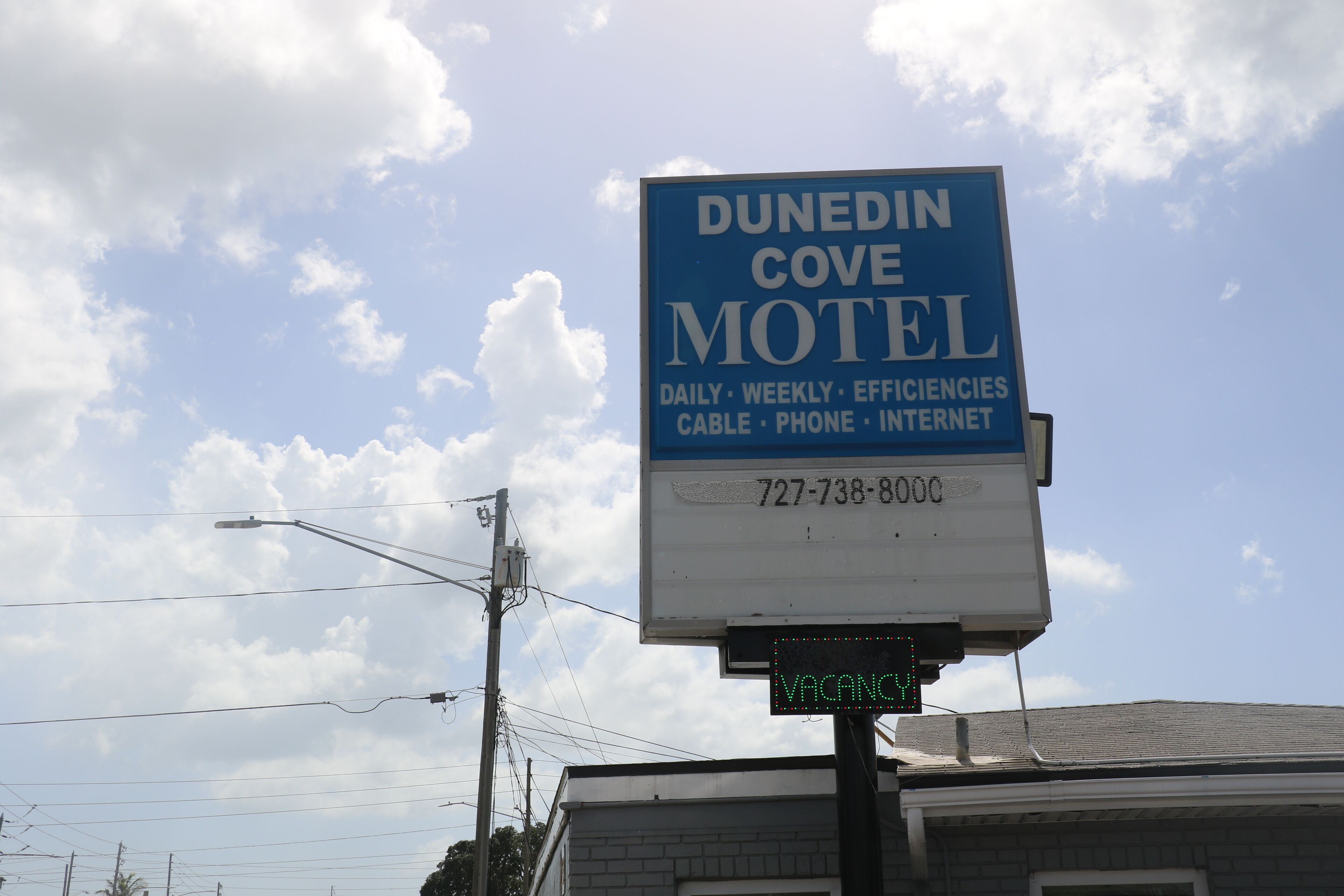 Un panneau indiquant un motel, avec l’inscription « DUNEDIN COVE MOTEL » et un numéro de téléphone.