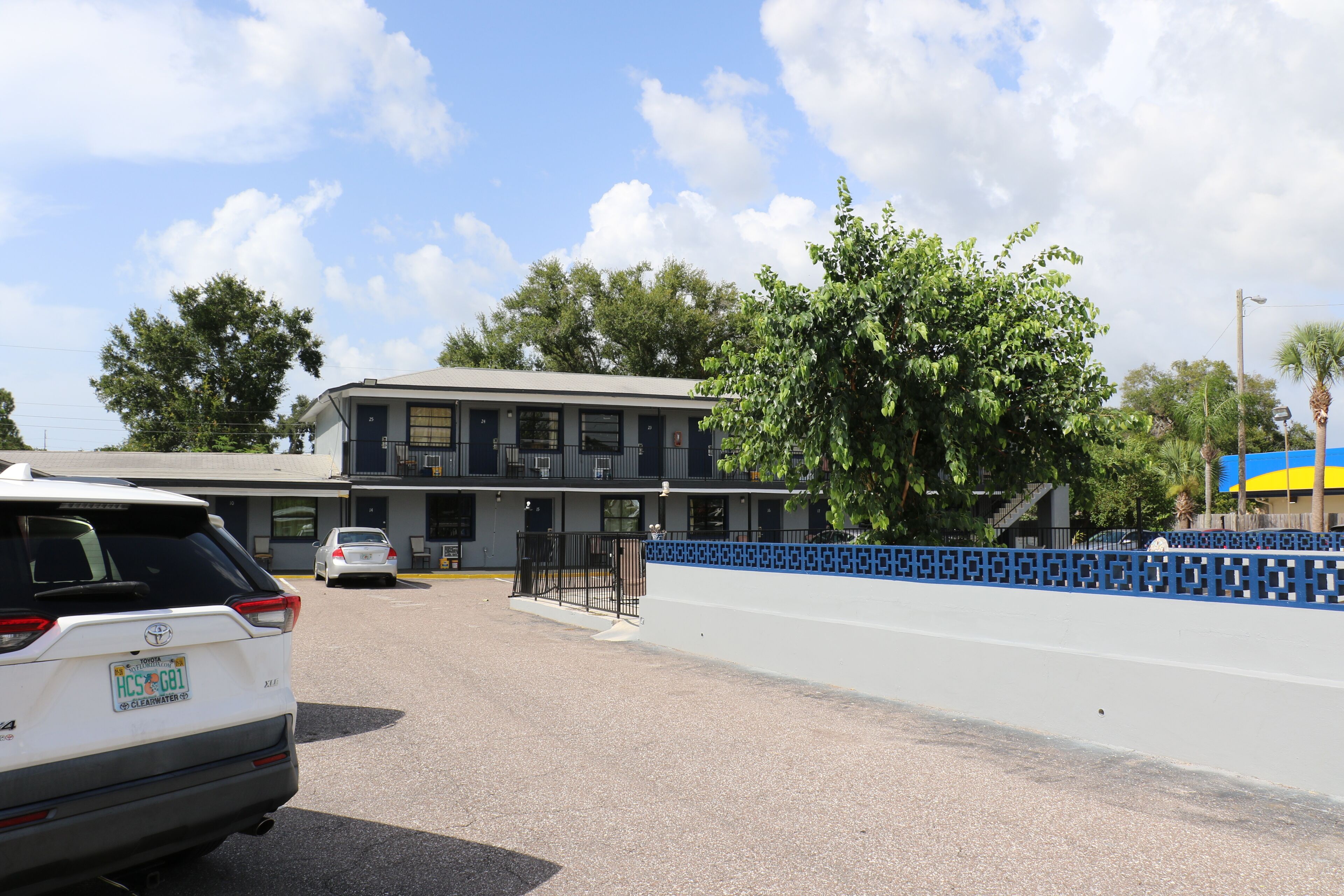 A building with a flat roof, large windows, and a blue decorative fence.