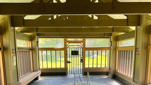 Une piscine couverte dotée d’une terrasse en bois, d’un portail en métal et offrant une vue sur l’extérieur.