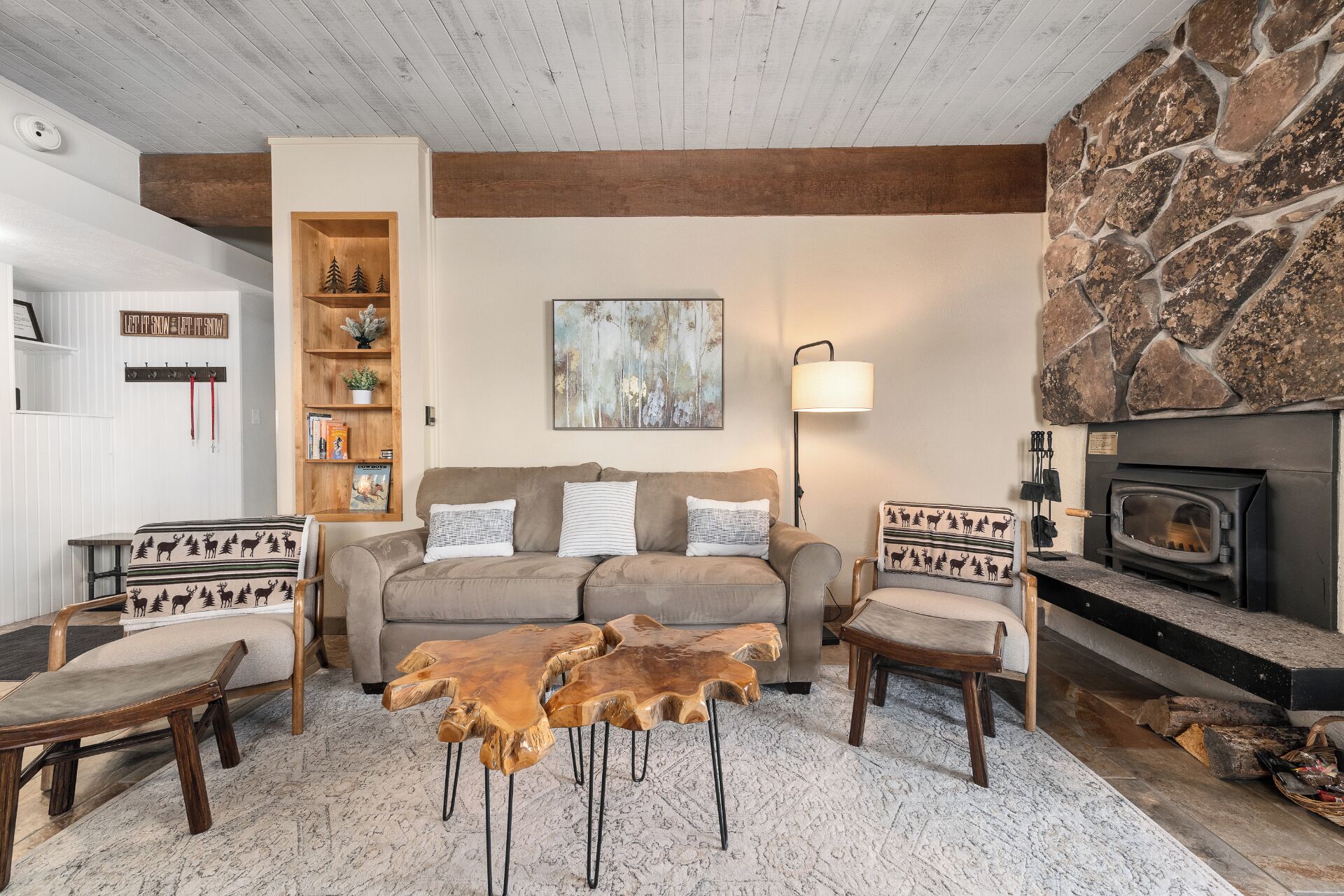 Ein gemütliches Wohnzimmer mit Kamin aus Stein, einem Holzregal, einer Couch und einem Couchtisch.