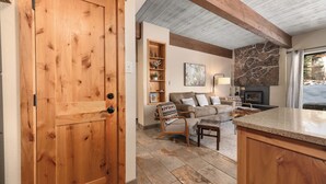 A cozy living room with a stone fireplace, a wooden door, and a stone-tiled floor. - Ski In Ski Out, Steps from the Slopes + Club Amenities (Steamboat Springs)