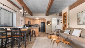 A cozy living room with a sofa, coffee table, and a dining area with chairs and a table. - Ski In Ski Out, Steps from the Slopes + Club Amenities (Steamboat Springs)