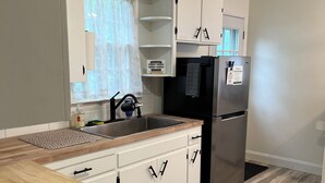 A modern kitchen with white cabinets, a stainless steel refrigerator, and a wooden countertop. - Charming 3-bedroom family friendly home in York (York)