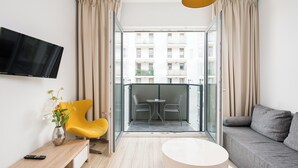 A modern living room with a sofa, a yellow chair, a round table, and a TV mounted on the wall. - Varsovia Comfort 939 (Warszawa)