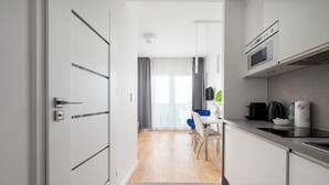 Et moderne køkken med mikrobølgeovn, komfur og kaffemaskine. Der er et spiseområde med bord og stole.