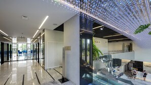 A modern lobby with a glass staircase, a sign for 'RACJA', and a clean, reflective floor. - Varsovia Comfort 922 (Warszawa)