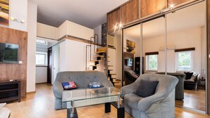 Una sala moderna con una mesa de centro de vidrio, sofás grises y piso de madera.