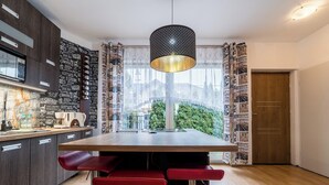 Una cocina moderna con una mesa de madera, taburetes rojos y una lámpara colgante.