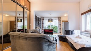 Una habitación moderna con sofá, cama, zona de comedor y vistas a espacios verdes.