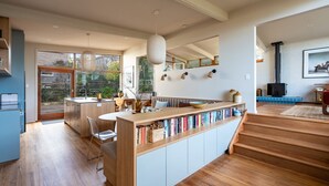 A modern kitchen with a wooden island, a dining area with a table and chairs, and a large window providing a view of the outdoors.