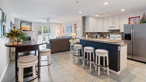 A modern kitchen with a central island, bar stools, and a refrigerator.