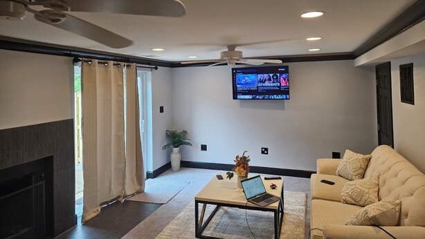 Una sala de estar moderna con un televisor de pantalla plana montado en la pared, un ventilador de techo y un sofá.