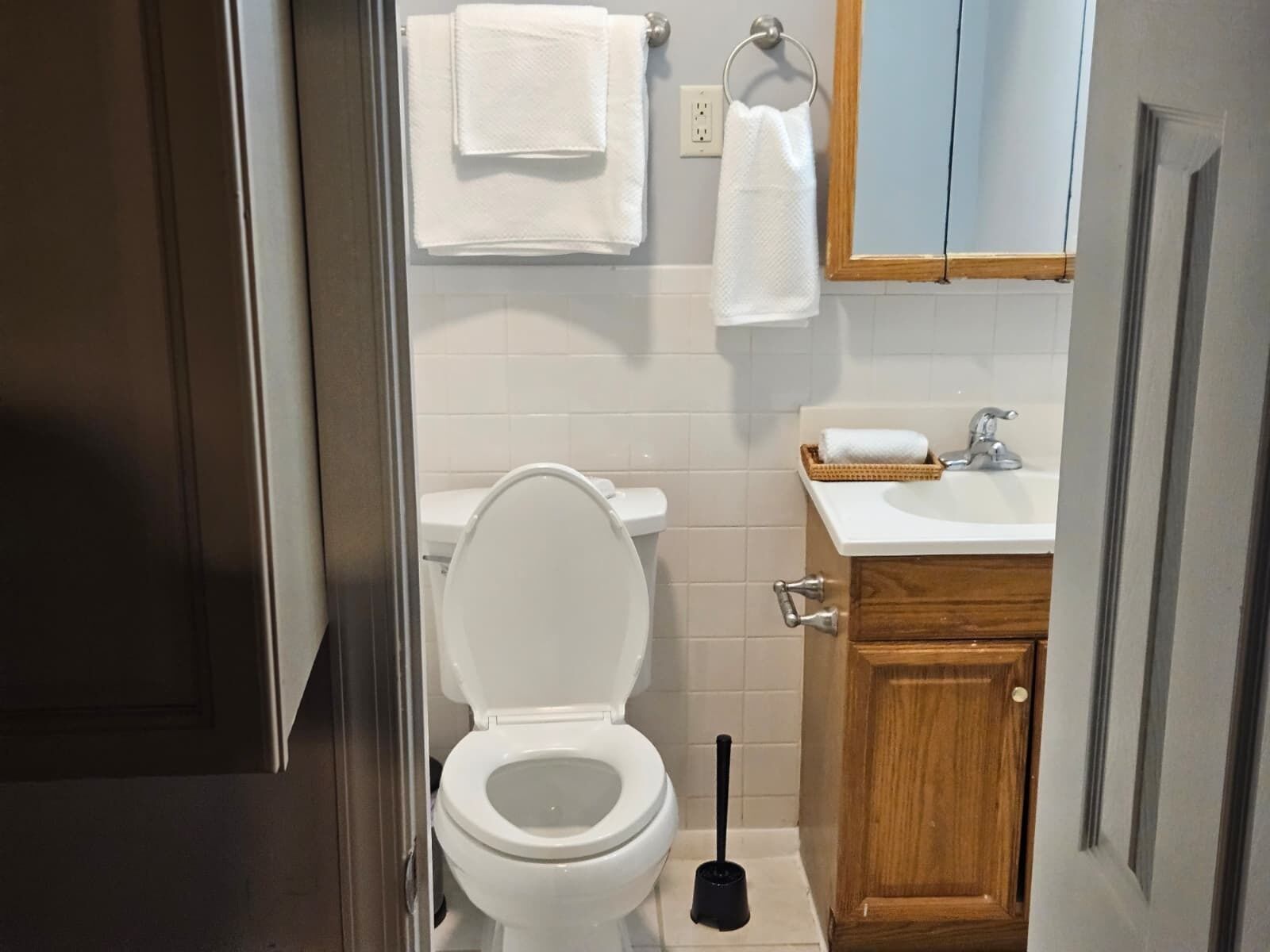Een badkamer met toilet, wastafel en een houten kast.
