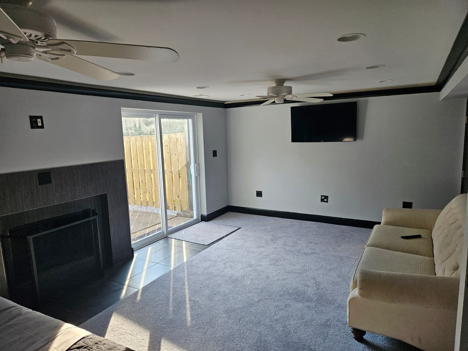 A spacious living room with a fireplace, a ceiling fan, and a sliding glass door leading to a patio.