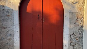 Une porte rouge en arc de cercle, avec un mur en pierre et une entrée pavée de pierres.