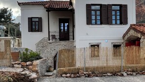 Un bâtiment à deux étages, doté d’un escalier en pierre menant à une porte en bois, d’un balcon et d’un petit muret en pierre surmonté d’une clôture en bois.