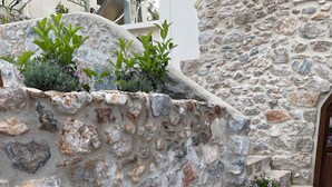 Un mur en pierre agrémenté de plantes en pot, un sol en pierre et une porte en bois.