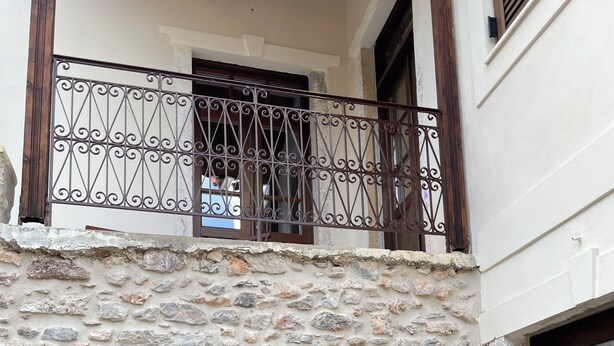 Une façade en pierre avec une porte en bois et un balcon doté de balustrades en fer forgé.