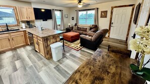 A spacious living area with a kitchen, a large island, a sofa, and a dining table. - Drew’s Delight - Relax in Comfort!  Modern, Fully Remodeled, No Stairs! (Mountain Grove)